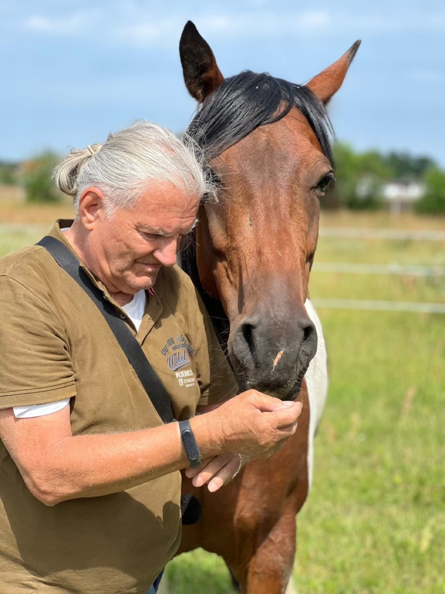 Kurt Walter im ruhigen Kontakt mit einem Pferd auf der Weide